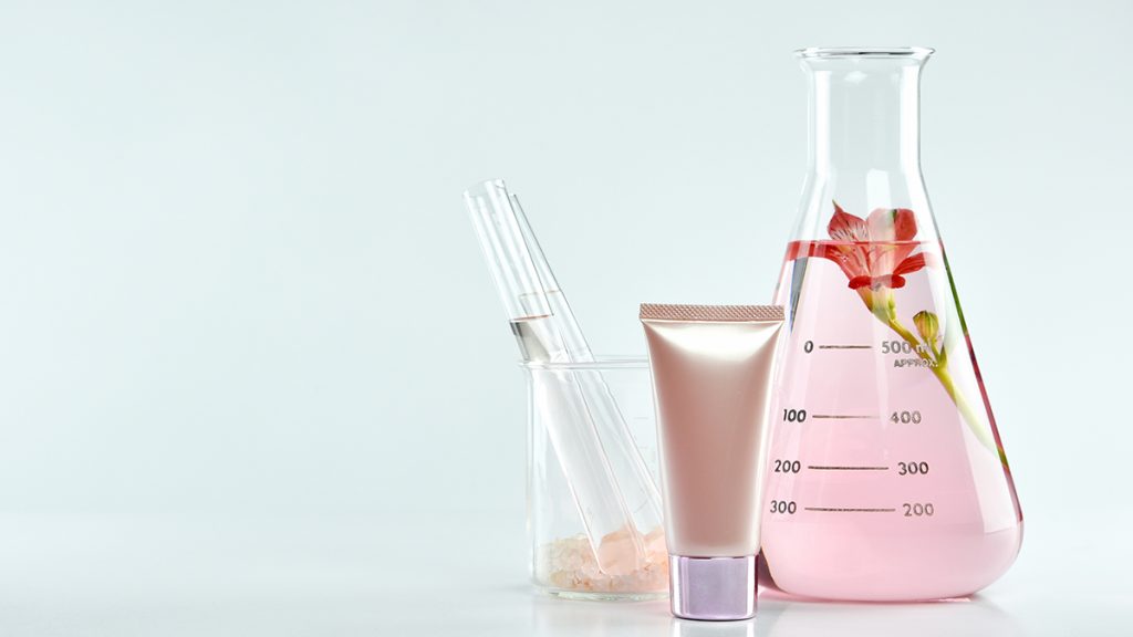 A laboratory setup featuring a beaker with powders, test tubes, and a flask containing a pink liquid, against a light gray background.