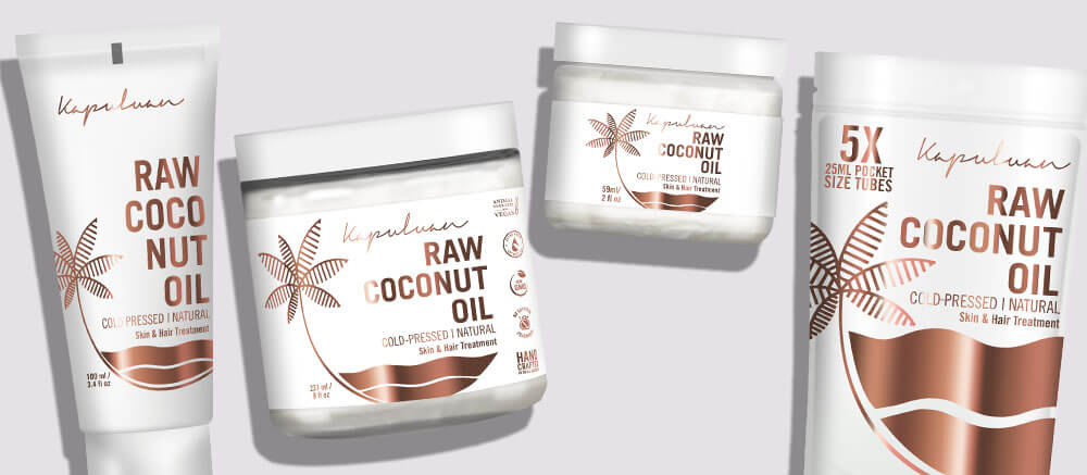 Four containers of kayo klearn raw coconut oil products, featuring two tubes and two jars against a grey background, emblazoned with botanical designs and text detailing the product type and benefits.
