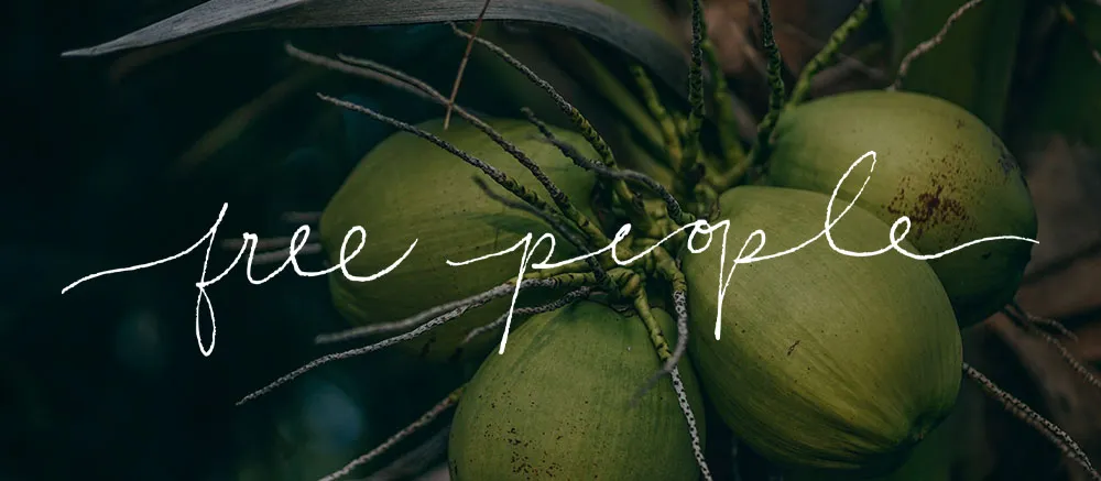 Close-up photograph of green coconuts hanging from a tree, with the phrase "free people" written in a stylized white cursive font across the middle of the image. The background is a mix of green and dark hues, creating a tropical atmosphere.