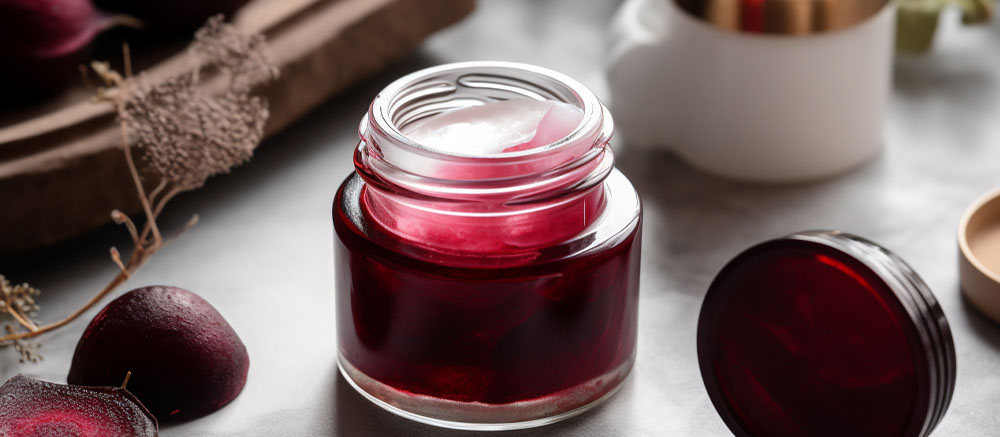 A jar of homemade plum jam on a kitchen counter, with fresh plums and a white cup nearby, implying fresh preparation and natural ingredients.