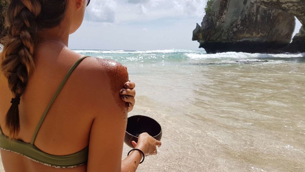 Woman enjoying her coconut oil body scrub and minimalist lifestyle at the beach.
