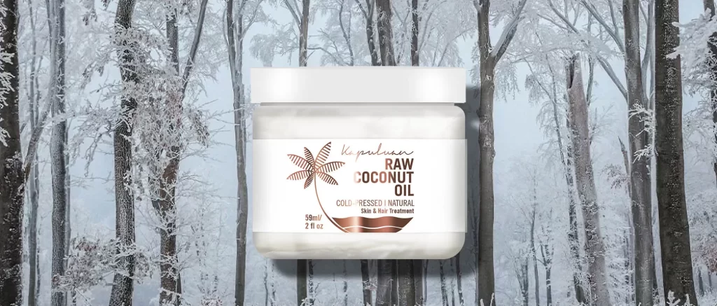 A bottle of raw coconut oil is displayed against a snowy, winter forest background. The label on the bottle reads, "Kapuluan Raw Coconut Oil, Cold-Pressed, Natural, Skin & Hair Treatment." The bottle contains 59 ml (2 fl oz) of the product.