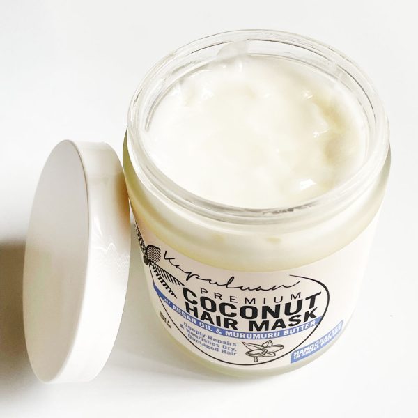 An open jar of Coconut Hair Mask with Argan and Murumuru placed on a white surface, showing the creamy texture inside the jar.