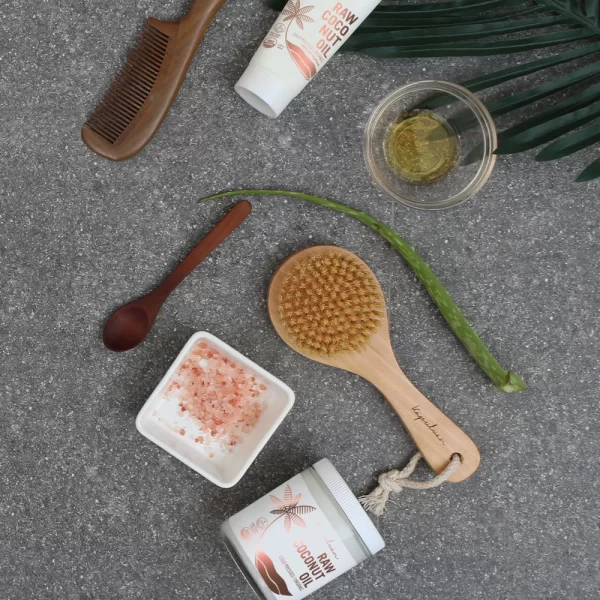 A collection of Vegan Sisal Dry Body Brushes arranged neatly on a textured surface, accompanied by a fresh aloe vera leaf, a green plant frond, and coconut elements, evoking a sense of natural beauty and self-care.