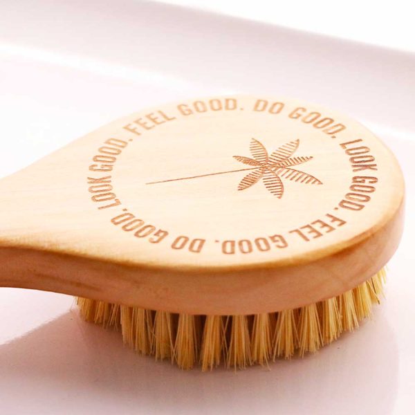 A wooden brush with natural coconut bristles featuring an etched mantra "look good. feel good. do good." around a simple floral design, promoting a positive self-care message.