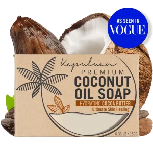 A bar of Coconut Oil Soap with Hydrating Cocoa Butter is displayed against a background featuring a split-open coconut and cocoa beans. The packaging includes the text "As Seen in Vogue" in a blue circle on the top right corner.