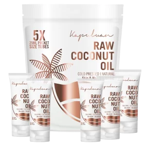 Image shows a large white container labeled "Kapuluan Raw Coconut Oil" in the background, along with five smaller 25ml pocket-size tubes with the same branding displayed in front. The design incorporates an illustration of a palm tree and highlights its use as a cold-pressed, natural product for skin and hair.