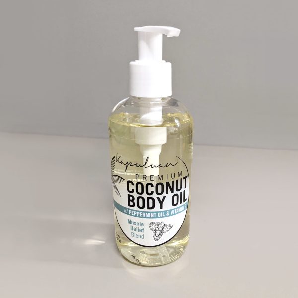 A transparent bottle of Muscle Relief Coconut Body Oil with a white pump dispenser, labeled prominently in black, featuring peppermint oil and vitamin e ingredients. the oil appears light yellow and the background is grey.