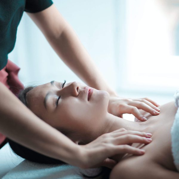 A person receiving a relaxing neck and shoulder massage with Coconut Body Oil Muscle Relief in a tranquil setting.
