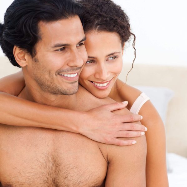 A smiling couple embracing, conveying warmth and affection as they hold a Sensual Coconut Body Oil together.