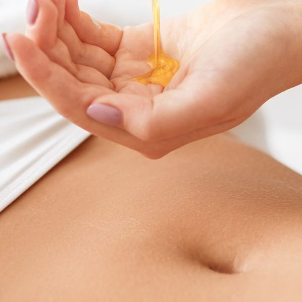 A person pouring Sensual Coconut Body Oil into their hand for skincare or massage.