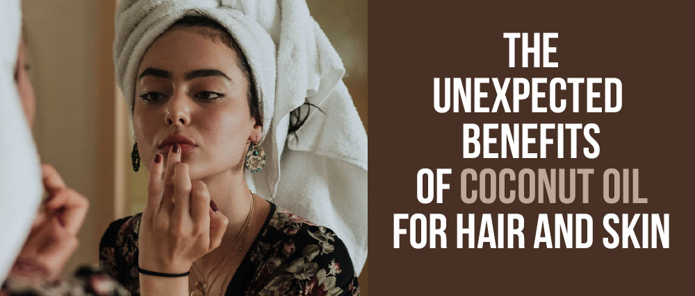 A woman with a towel on her head applies coconut oil to her lips while looking into a mirror; text reads "the unexpected benefits of coconut oil for hair and skin.