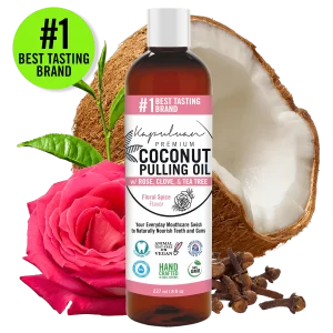 A bottle of Coconut Pulling Oil - Floral Spice is displayed in the center, surrounded by a halved coconut, a pink rose, and cloves. The label highlights floral spice flavor, vegan, non-GMO, and handcrafted certifications. "#1 Best Tasting Brand" is noted.