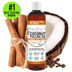 Image of Coconut Pulling Oil - Pumpkin Spice. The 237 ml bottle is surrounded by cinnamon sticks, a coconut half, and cloves. Labels indicate it's the "#1 Best Tasting Brand" and highlight features such as being vegan, non-GMO, and hand-crafted.